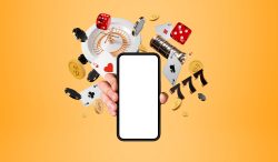 En hand håller i en smartphone. I bakgrunden syns spelbrickor, spelautomater, tärningar och så vidare.
