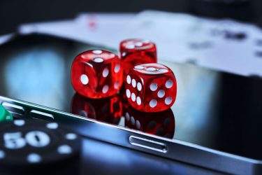 Tre speltärningar ligger på en smartphone.